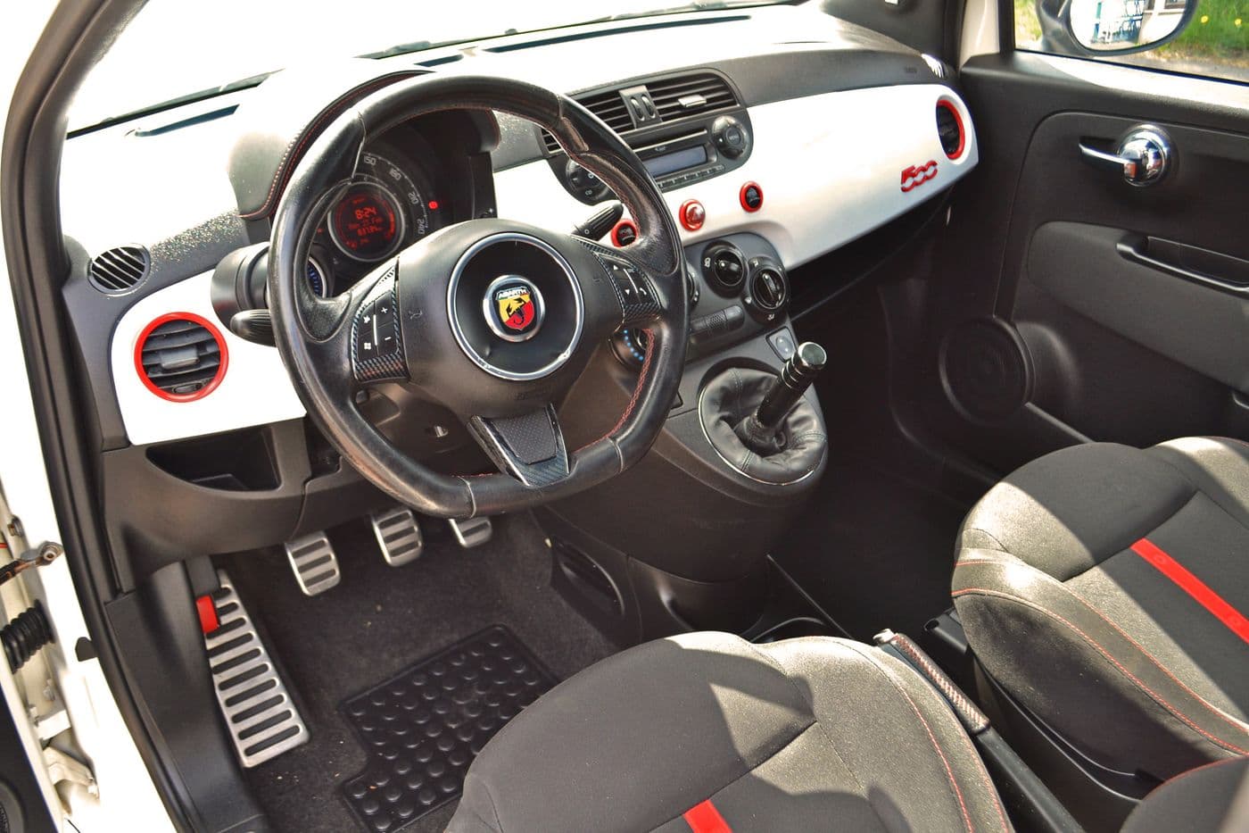 Umfangreiche und moderne Innenausstattung des Abarth 500 mit schwarzem Leder und roten und weißen Akzenten.