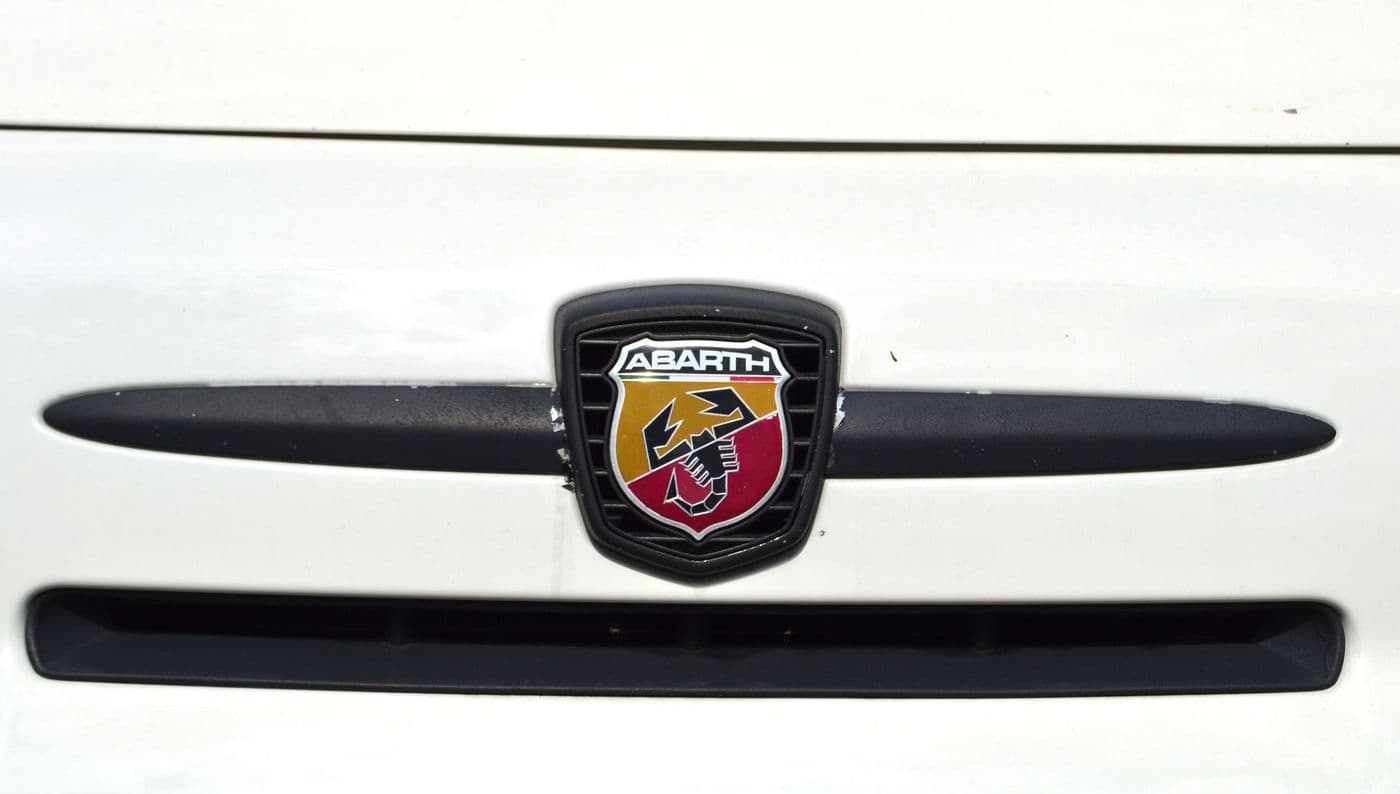 Nahaufnahme der Front des weißen Abarth 500 mit Blick auf das Markenzeichen "Scorpion Logo auf gelb-rotem Wappen".