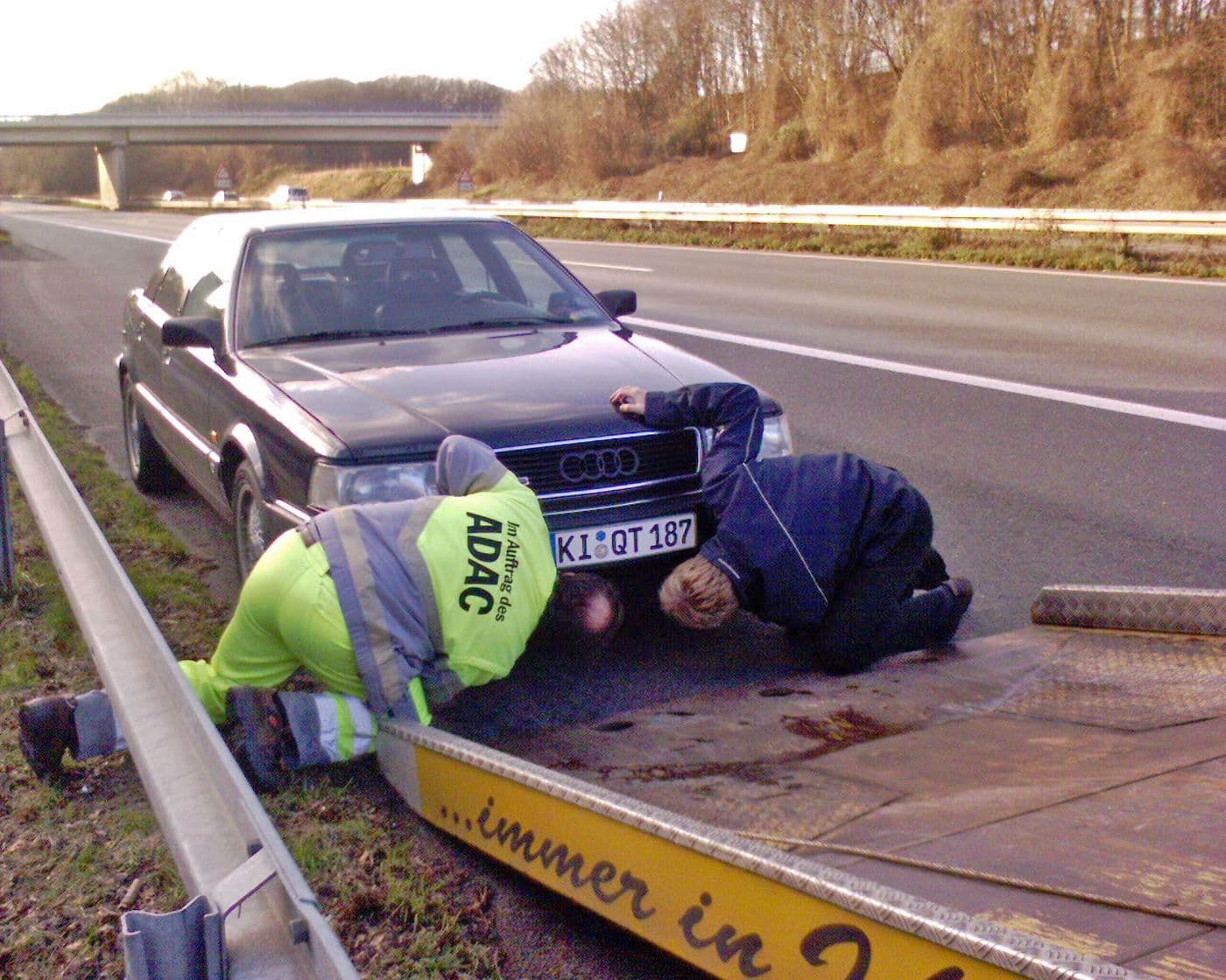 Audi v8 hat eine Panne auf der Schnellstraße und wird von zwei ADAC-Mitarbeitern auf das Abschleppfahrzeug verladen. 