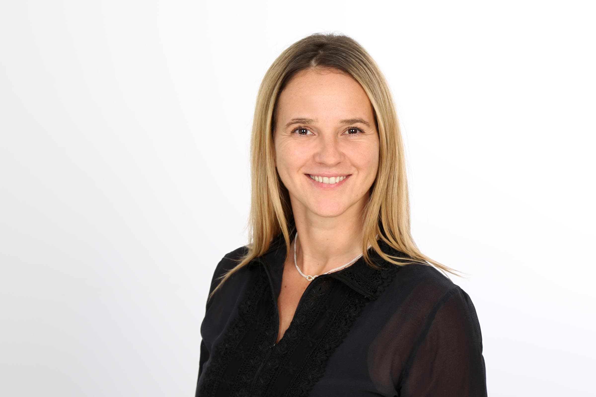 Daniela Zierold, Head of Marketing, Brand Management und Communications bei Hiscox, lächelt in die Kamera. Sie trägt eine schwarze Bluse, eine Halskette und hat blonde Haare.