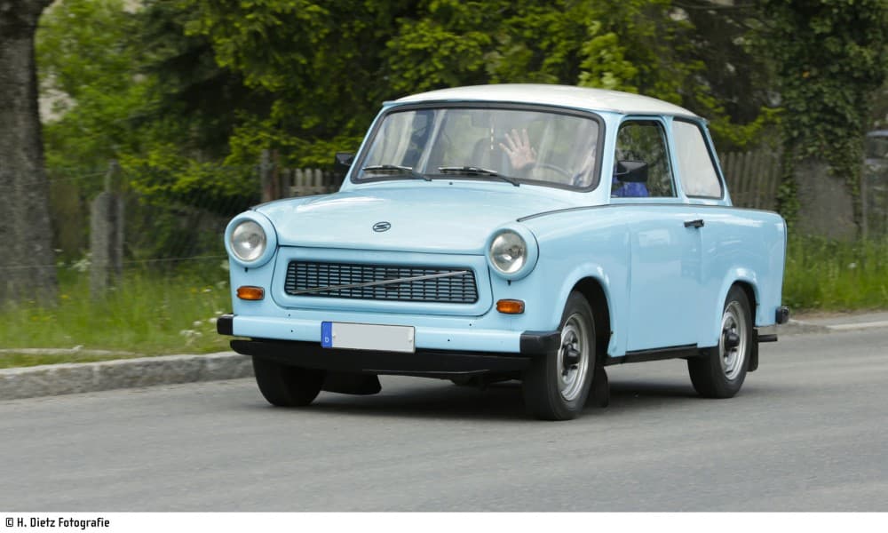 Ein Trabant 601 in hellblau fährt auf der Straße.