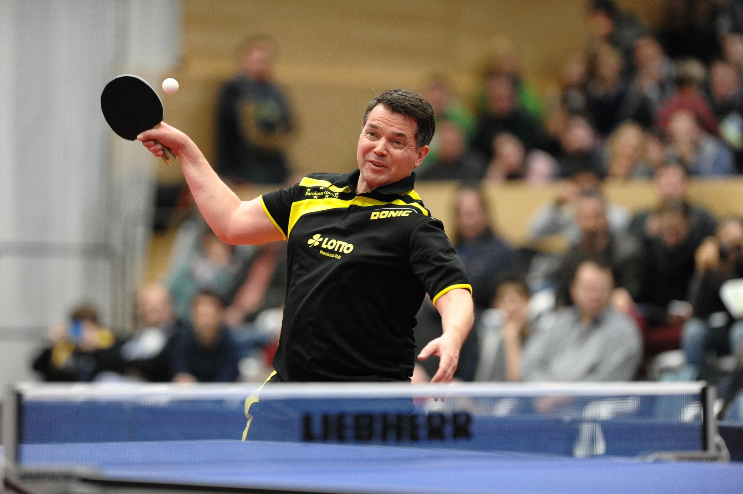 Steffen Fetzner beim Tischtennis spielen in Action. Er trägt ein schwarz-gelbes Trikot 