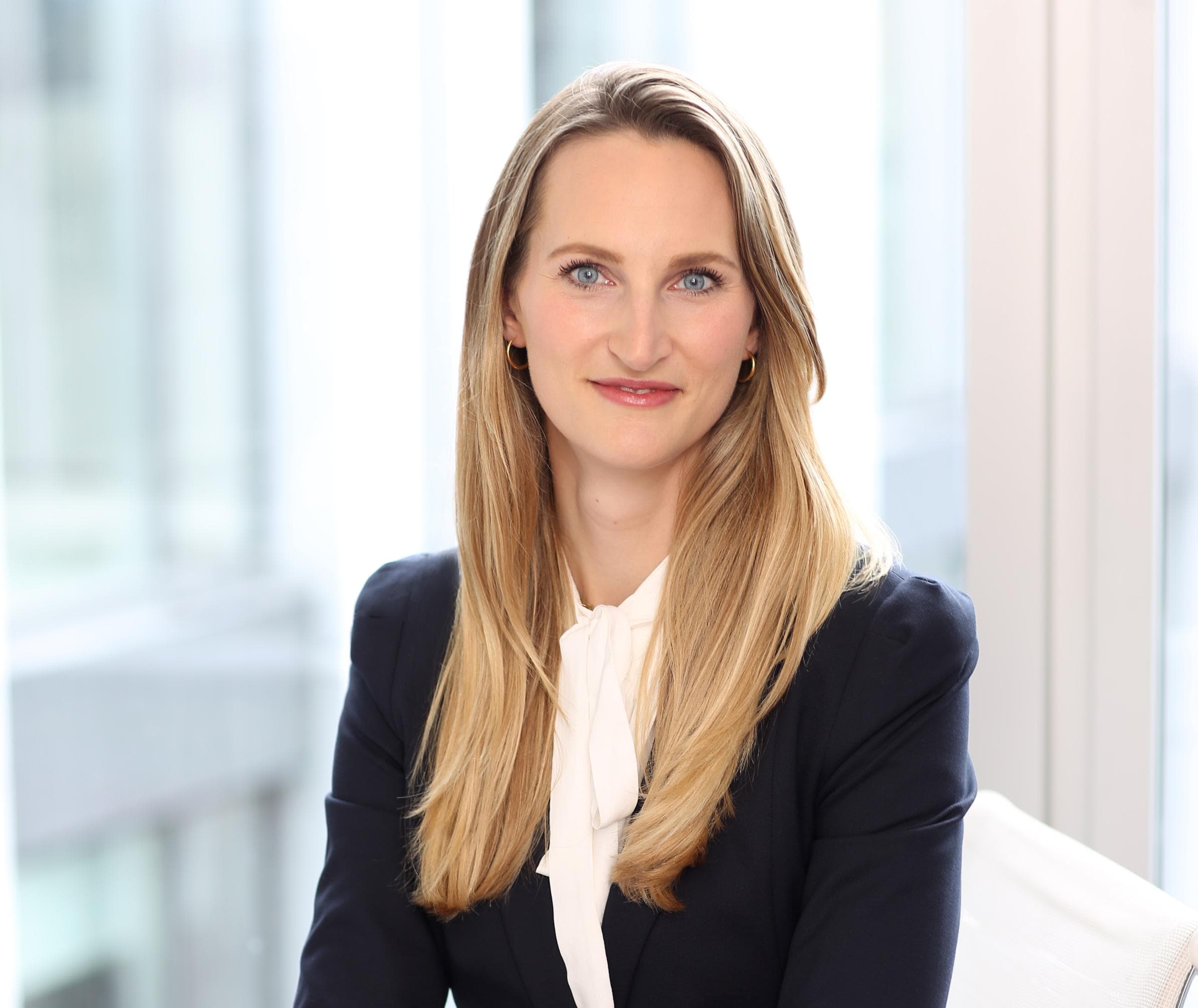 Gisa Kimmerle, Product Head von Cyber bei Hiscox, lächelt in die Kamera. Sie trägt eine weiße Bluse mit schwarzem Blazer und hat blondes Haar.