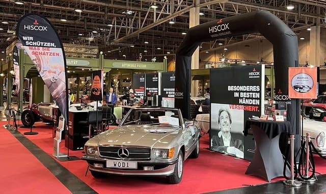 Blick auf den Messestand von Hiscox au der Oldtimer Fachmesse in Essen 2024mit Blick au ein Oldtimer-Model und Messeaufsteller