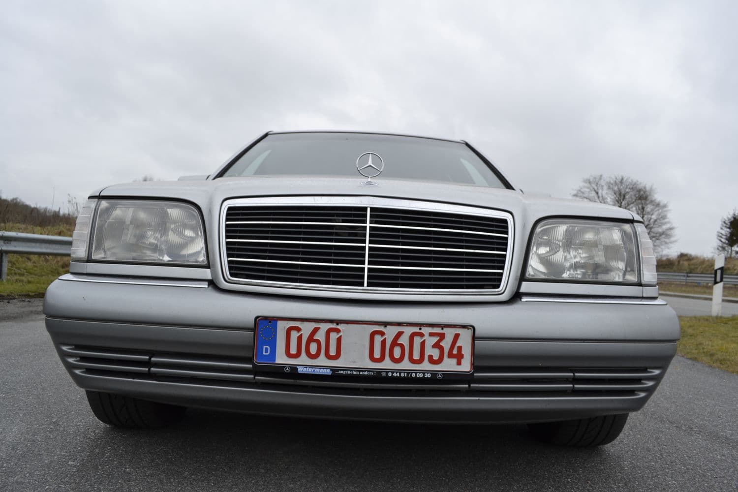 Mercedes W140 S320 Totale in grau parkt auf einer Straße bei Regenwetter mit Blick auf die Front des Fahrzeugs