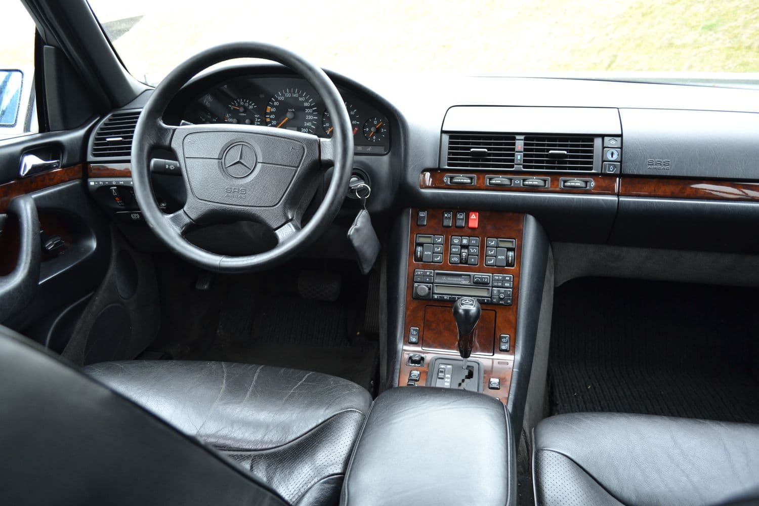 Einblick in das Interieur des Vorderbereiches des Mercedes w140 s320 mit schwarzen Ledersitzen und brauner Innenverkleidung