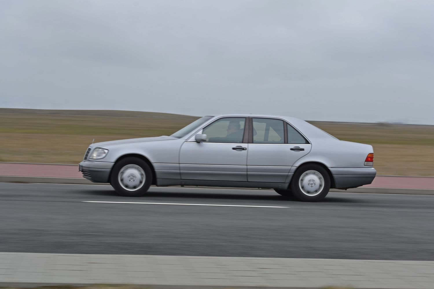 Aufnahme eines grauen Mercedes W140 S320 im Driveby auf einer gepflasterten Straße