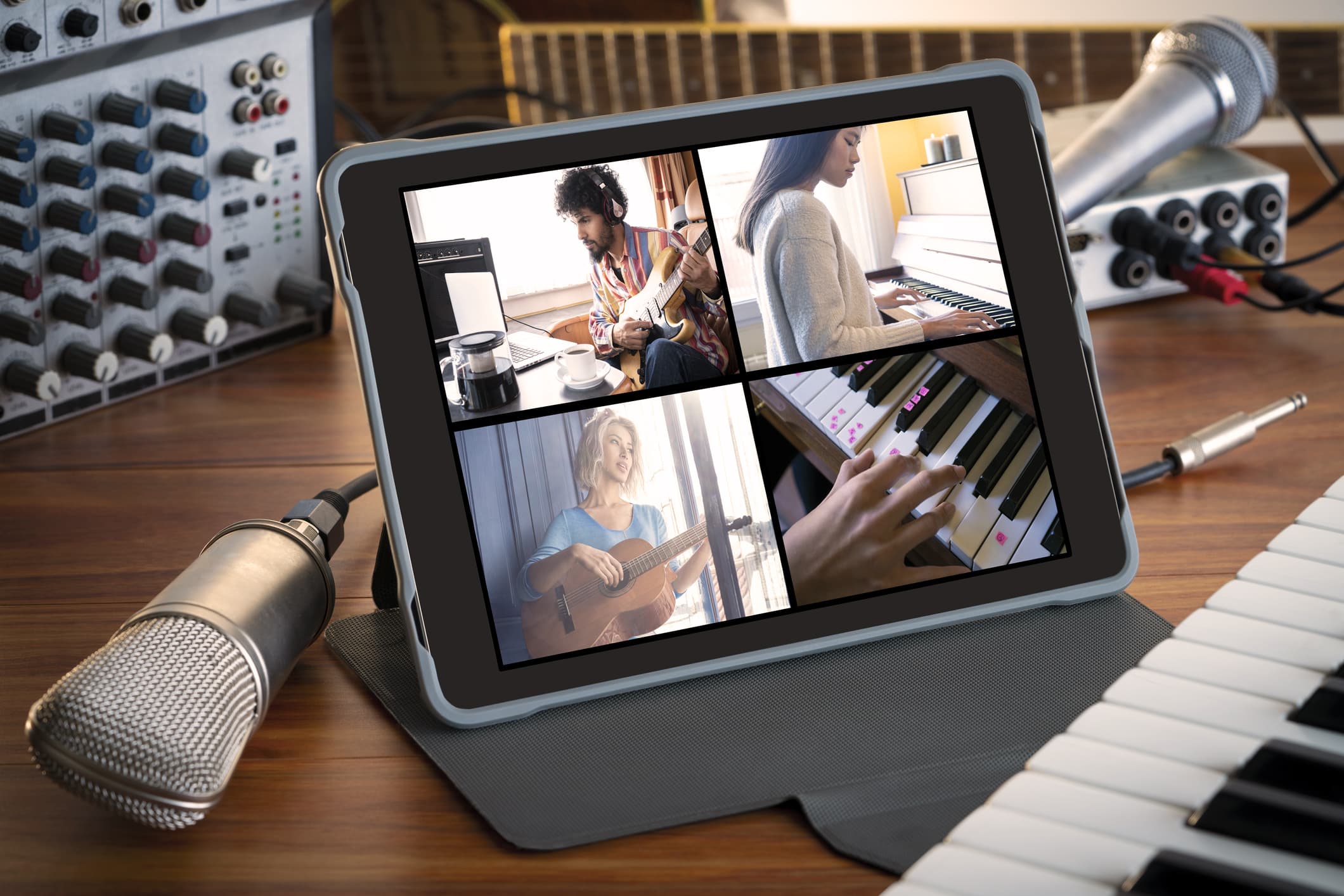 Auf dem Schreibtisch steht ein Tablet, bei dem gerade eine Videoübertragung von vier Musikern stattfindet